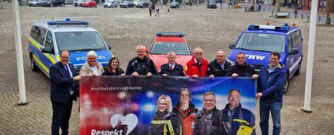 Petra Kirner, Ostholsteiner Kreispräsidentin, präsentiert mit Vertreterinnen und Vertretern von Feuerwehr, THW, Polizei und DLRG das neue Banner "Respekt für Retter".